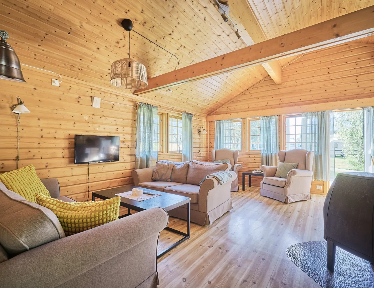 Bilde av stova med sofa, TV og vedovn i feriehyttene på Tjugen camping3